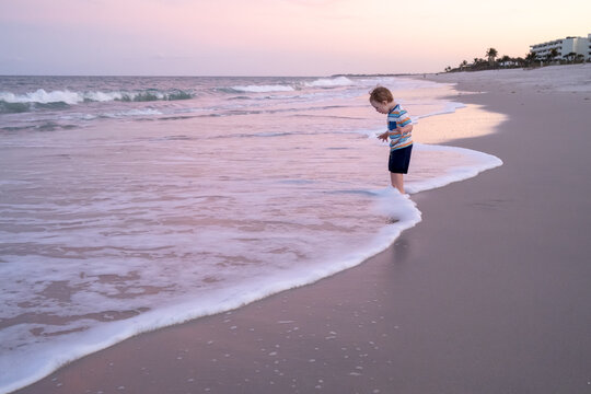 Toddler playing on beach in the ocean surf