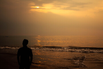 silhouette of a person walking on the beach at sunset