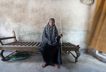 Portrait of blind muslim woman seated in her home.