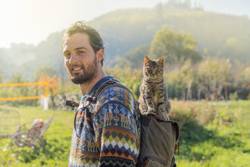 A man with a cat on top of his backpack