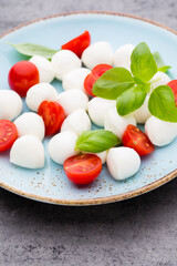 Delicious caprese salad with ripe cherry tomatoes and mini mozzarella cheese balls with fresh basil leaves.