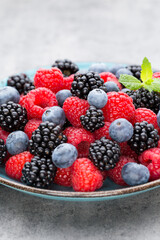 Fresh berry salad on blue dishes. Vintage wooden background.