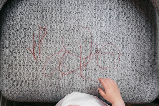 Anonymous toddler coloured on an armchair
