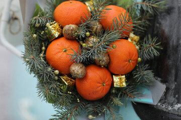 Fototapeta na wymiar Christmas bouquet of fir branches, mandarins and little gift boxes on blue background. New Year.