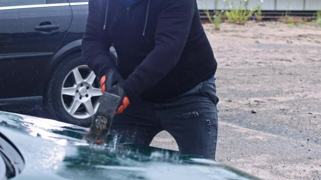 Angry man breaking car with big hammer. Concept of terror and vandalism. High quality 4k footage