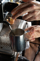 Closeup female hands are making coffee using professional metal machine in cafe.