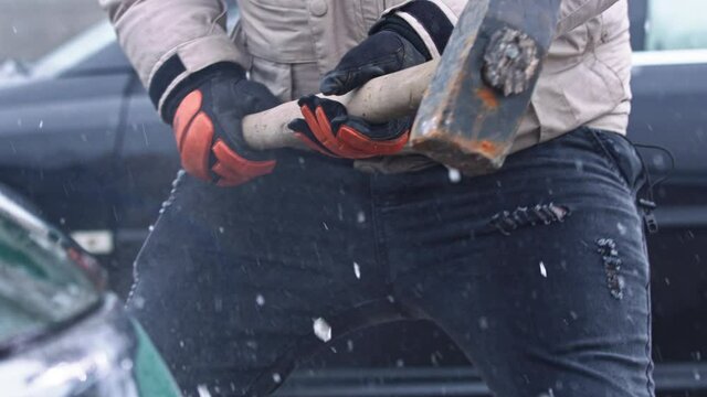Angry man breaking car with big hammer. Concept of terror and vandalism. High quality 4k footage