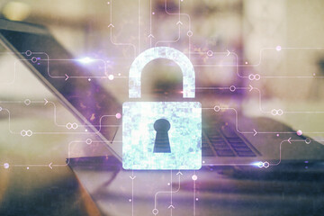 Double exposure of desktop with computer and lock icon hologram. Concept of data safety.
