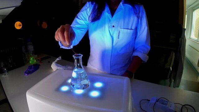 A woman scientist is working in a laboratory with fluorescent compounds for the development of an anticancer drug