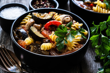 Pork ragout with fusilli and champignon on wooden table
