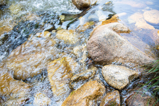 beautiful detail of brilliant water flowing on rocks in bed of river