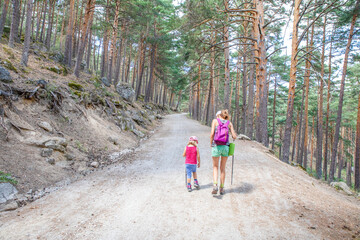 from behind little girl and woman hiking trail in forest of Canencia mountain