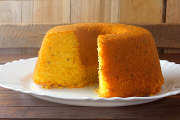 corn cake sliced on white plate on rustic wooden table. Typical Brazilian food. Front view