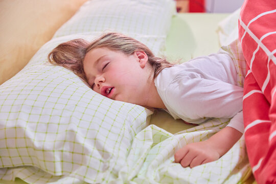 face of blonde caucasian five years old girl, with open mouth and funny expression    sleeping on king bed