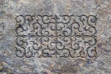 Ornamental print on the stone surface. Vintage ornament on the stone. Close-up seamless texture. Stone texture. Pattern on the stone. Embossed pattern. Wallpaper.