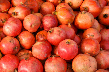 fresh harvestedred red pomegranate fruits lying on a heap in a store