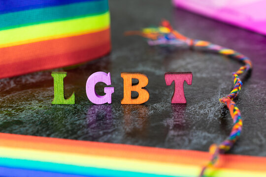 Gay pride letters LGBT rainbow ribbon on gray-black background