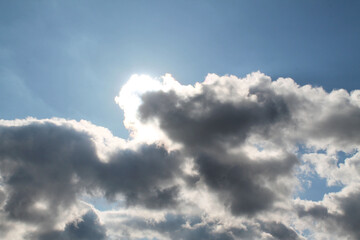 The blue sky is covered with dark clouds, close-up, bottom view. The rays of the sun shine through the gray clouds. Autumn day.