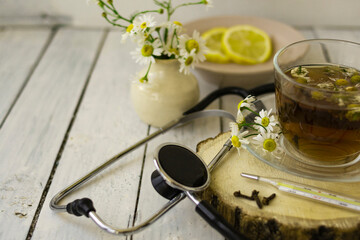 Decoction of chamomile, dried flower in flower tea and a phonendoscope, sliced lemon on a white...