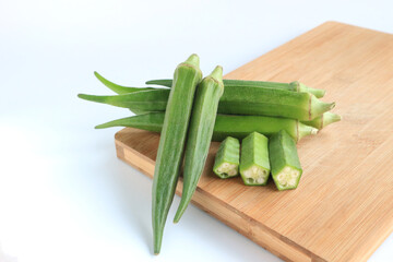 Fresh vegetable okra on wooden tray on white background