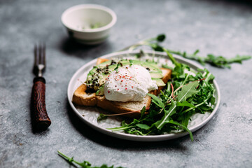 Poached egg with avocado salad, microgreen and arugula