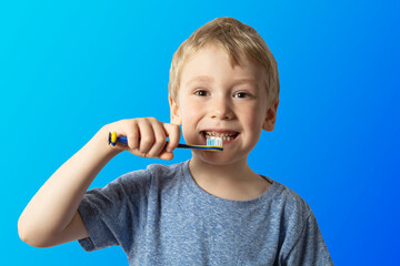 a boy with white hair holds a toothbrush in his hands wants to brush his teeth. blue background.