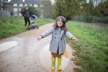 Obraz premium Happy little girl smiling adorably after jumping in a muddy puddle
