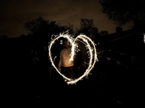 Man Standing With Heart Shape Light Painting At Night
