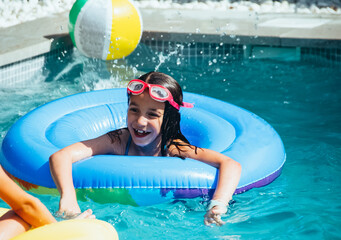 Portrait of a little girl having fun in a swimming pool with a floater. Fun concept