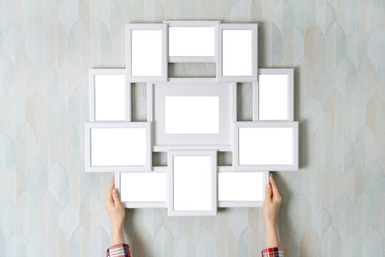 Blank empty frame for multiple photos in female hands, as mockup for your design. Girl hangs a frame on the wall.