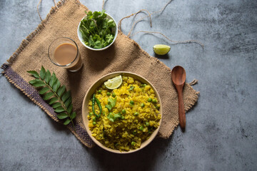 A bowl of poha along with a glass of tea, a typical Indian breakfast with use of selective focus.