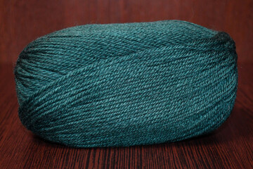 a skein of green yarn in close-up on a dark background. The texture of the yarn.