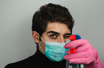 hombre joven con mascarilla guantes y desinfectante limpiando