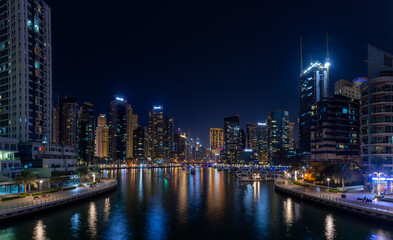 Dubai Marina Yacht Club long exposure panorama at night with lights of skyline and creek for luxury vacation and travel