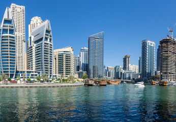Dubai Marina skyline panorama with yachts and dhow boats during the day with blue sky along the promanade near Jumeriah