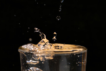 Gotas de agua cayendo sobre vaso rebosante