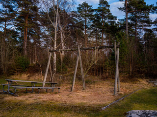 Swings and a bench in an empty summercamp. It is early spring with no people around.