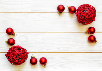 A frame of red baubles on a white wooden background with copy space.