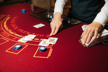 Croupier hands dealing cards on t blackjack poker table, gambling table with cards and chips - obrazy, fototapety, plakaty