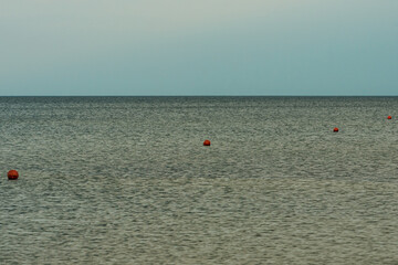 calm water surface on which orange buoys fly