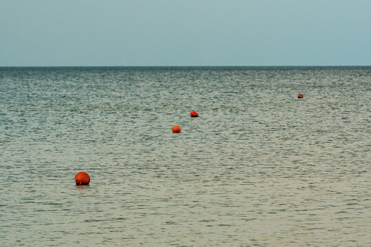 calm water surface on which orange buoys fly