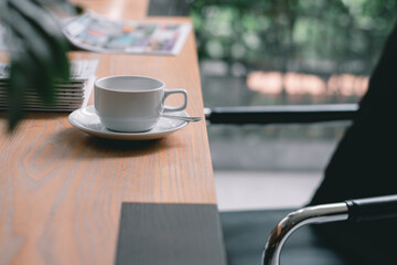 Coffee​ cup​ on the wood desk by the window with the bright light of the morning sun in the office or house,Cozy atmosphere is for relaxing on vacation,charge energy to refresh the body to working.