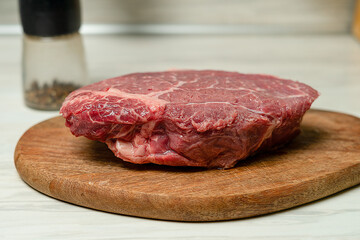 Marbled beef steak with role lies on a wooden board in the kitchen