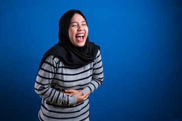 Naklejka na ściany i meble muslim woman laughing hard while holding her belly, happy excited expression