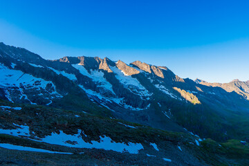 Landscape mountain view peaks in snow and green hills, deep blue sky and huge white clouds background, Hohe Tauern Austrian Alps, Europe