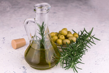 Olive oil decanter and rosemary branches on a white background.