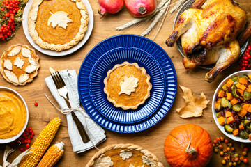 Pumpkin mini pie served on a dark blue plate, top down view of Thanksgiving table setting