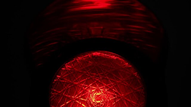 Half of a red alert stoplight of a traffic light or a semaphore at night in the city. Black background.