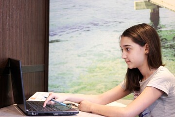 a girl studies on a laptop at home