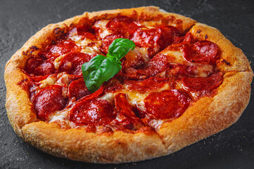 Pepperoni Pizza with Mozzarella cheese, salami, Tomato sauce, pepper, Spices. Italian pizza on Dark grey black slate background